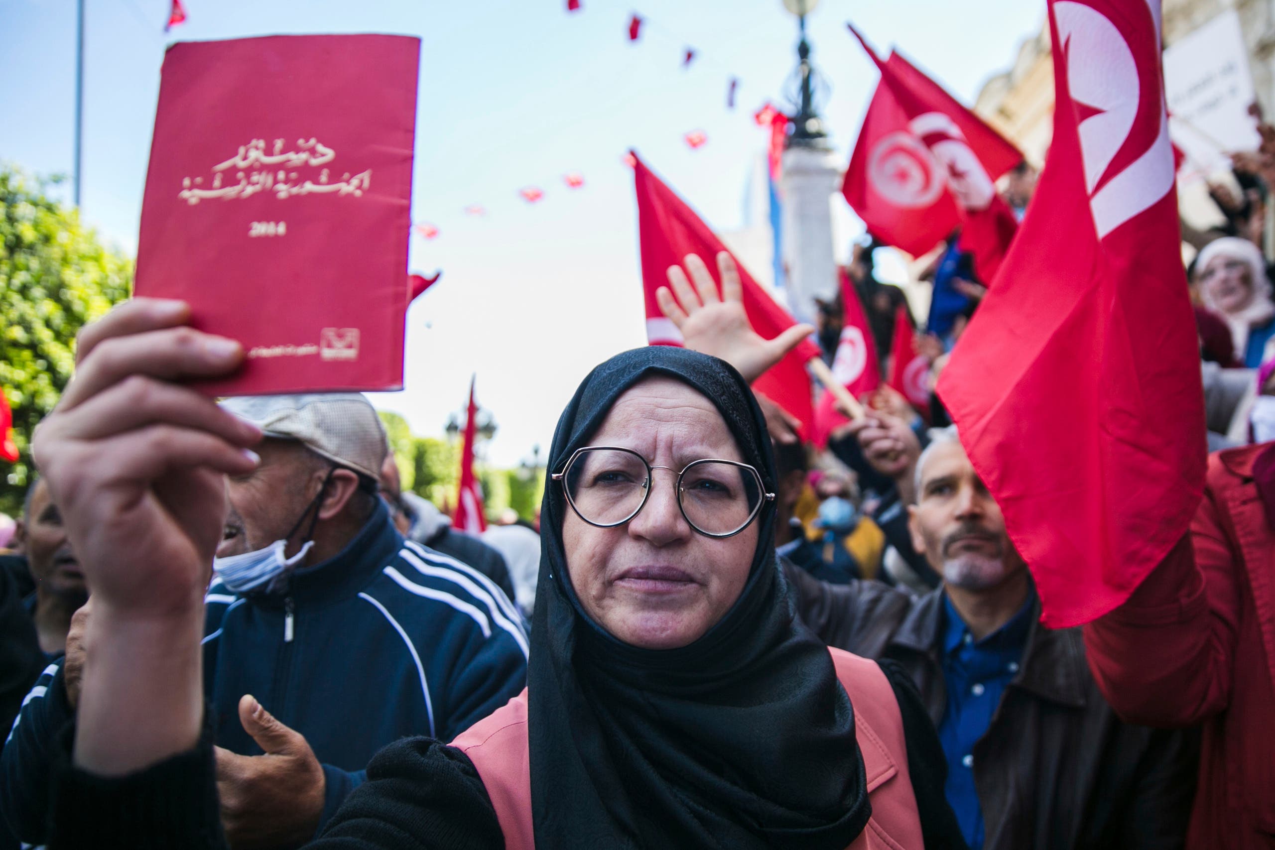 سيدة ترفع الدستور التونسي في مظاهرة مناهضة لسعيد في ابريل الماضي