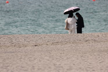 سيدات يحتمين تحت مظلة قرب البحر وسط درجات حرارة قياسية في الإمارات